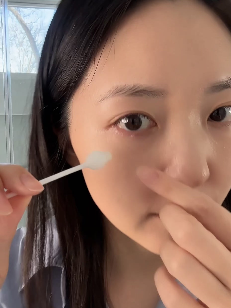 person-applying-botanical-eyelid-cleanser-using-cotton-swab-applicator